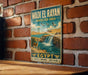A vintage-style metal sign with a waterfall and wildlife, mounted on a brick wall.