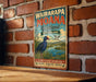 A vintage-style metal sign for Waiarapa Moana Wetland in New Zealand, featuring a bird and a scenic landscape.