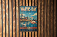 A vintage metal sign for Walvis Bay, Namibia, featuring a pink flamingo and a coastal cityscape.