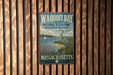 A metal sign with the text "Waqoit Bay National Estuarine Research Reserve Massachusetts" is displayed on a wooden fence.