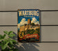 A vintage metal sign for Wartburg Castle in Germany, featuring an illustration of the castle and the text "Wartburg Castle" prominently displayed.