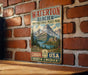 A vintage metal sign advertising Waterton Glacier International Peace Park, featuring a scenic mountain landscape with a lake and forest.