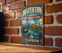 A vintage-style sign for Waterton Lakes Biosphere Reserve in Canada, featuring a scenic landscape with mountains, a lake, and a deer.