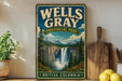 A vintage-style sign for Wells Gray Provincial Park in British Columbia, featuring a scenic image of a waterfall surrounded by pine trees and mountains.