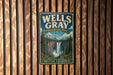 A vintage metal sign for Wells Gray Provincial Park in British Columbia, Canada, featuring a scenic image of a waterfall surrounded by mountains.