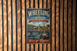 A vintage-style metal sign for the Wheeling National Heritage Area in West Virginia, featuring a scenic illustration of the area and text promoting the region's history and future.