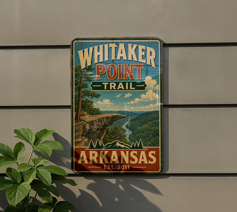 A vintage-style metal sign for Whitaker Point Trail in Arkansas, featuring a scenic landscape with a cliff and river.