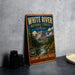 A vintage-style metal sign for the White River National Forest in Colorado, featuring a scenic mountain landscape with a river and pine trees.