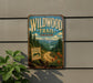 A vintage-style metal sign for the Wildwood Trail in Oregon, featuring a scenic mountain landscape with pine trees, flowers, and a winding road.