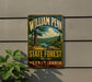 A metal sign with the text "William Penn State Forest Pennsylvania" displayed on a wall, featuring a scenic landscape with pine trees and a lake.