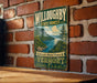 A vintage-style metal sign with the text "Willoughby State Forest Vermont" is displayed on a brick wall.