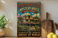 A vintage-style metal sign for the Winchester Mystery House in San Jose, California, featuring an illustration of the house and the text "Built in Mystery and to Baffle the Spirits Amaze the World!"
