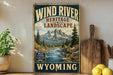A vintage-style sign advertising the Wind River Heritage Landscape in Wyoming, featuring a scenic mountain landscape with a winding river.