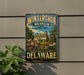 A vintage metal sign for the Winterthur Museum and Country Estate in Delaware, featuring an illustration of a historic building surrounded by trees and flowers.