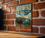 A vintage-style metal sign for Wood Buffalo National Park in Canada, featuring an illustration of a bison in a grassy landscape with a river and mountains in the background.