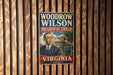 A vintage Woodrow Wilson Presidential Library poster is displayed on a wooden wall.