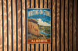 A vintage metal sign for Writing-On-Stone Provincial Park in Alberta, Canada, featuring a scenic landscape with a river and mountains.