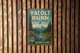 A vintage metal sign for Yacolt Burn State Forest in Washington, featuring a scenic image of a forest and a mountain.