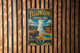 A vintage-style metal sign for Yellowstone National Park, featuring an illustration of a bison and a geyser, mounted on a wooden wall.