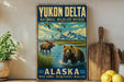 A vintage-style sign for Yukon Delta National Wildlife Refuge in Alaska, featuring a moose and a bear in a natural landscape with mountains in the background.