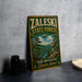 A vintage-style metal sign for the Zaleski State Forest in Ohio, featuring a scenic illustration of a forest landscape with a river and mountains.
