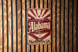 A vintage-style metal sign with the word "Alaska" prominently displayed, mounted on a wooden wall.