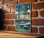 a vintage-style metal sign with a mountain and a ship, mounted on a brick wall.