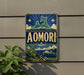 a vintage-style sign with the word "AOMORI" prominently displayed, along with a mountain landscape and a ship in the background.