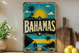 A vintage-style sign with the word "BAHAMAS" prominently displayed, featuring a tropical beach scene with palm trees, a sun, and a sailboat.
