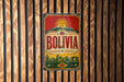 A vintage-style metal sign with the word "BOLIVIA" prominently displayed, featuring a sun and mountains in the background.