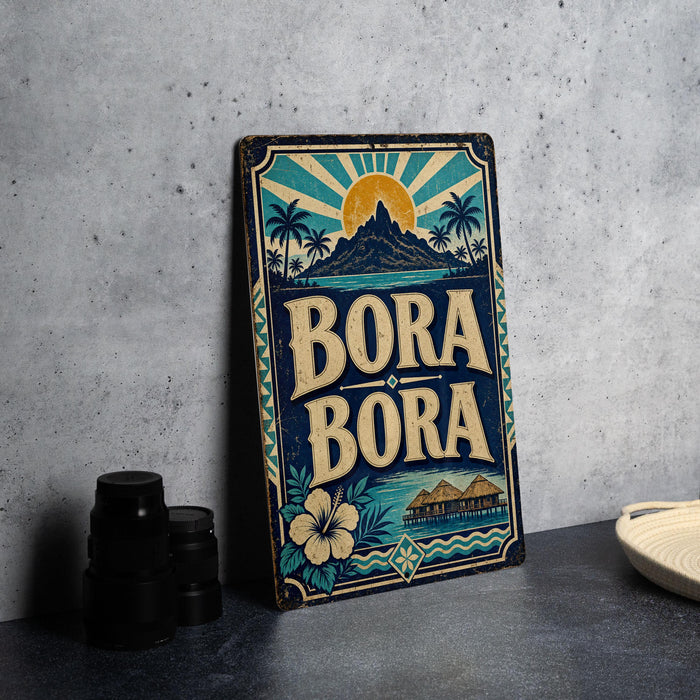 A vintage-style metal sign with the text "Bora Bora" is displayed on a gray countertop, with a stack of black camera lenses and a white dish visible to the side.