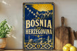a vintage-style metal sign with the text "Bosnia and Herzegovina" prominently displayed. The sign is set against a backdrop of a scenic illustration of a town and mountains, with a sunburst design above. The sign is placed on a wooden surface, and there are some potted plants and kitchen utensils visible in the background.