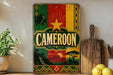 a vintage-style metal sign with the word "Cameroon" prominently displayed, surrounded by a colorful, tropical-themed design.