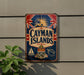 A vintage metal sign with the text "CAYMAN ISLANDS" and various decorative elements, including a Union Jack flag, a sailboat, and a turtle, is displayed on a wall.