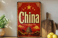 A vintage-style sign with the word "China" prominently displayed, featuring a traditional Chinese temple and mountains in the background. The sign is placed on a shelf next to a wooden cutting board and a potted plant.
