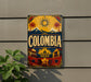 A vintage-style sign with the word "COLOMBIA" prominently displayed, featuring a sun, palm trees, mountains, and a colorful, decorative border.