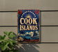 A vintage-style sign for Cook Islands, featuring a sailboat, palm trees, and a sun in the sky, mounted on a wall.
