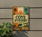 a vintage-style sign with a tropical theme, hanging on a wall next to a plant.