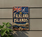 a vintage-style sign for Falkland Islands, mounted on a wall with a Union Jack flag and a seagull in the background.