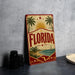 A vintage-style sign with the word "FLORIDA" prominently displayed, featuring palm trees, a sun, and a sailboat, all set against a beach scene.