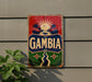 a vintage-style sign with the word "Gambia" prominently displayed, along with a tropical landscape and palm trees.