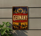 a vintage-style sign with the word "GERMANY" prominently displayed, along with an illustration of a city skyline and a crest.