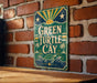 A vintage-style sign for "Green Turtle Cay" is displayed on a brick wall, featuring a turtle and palm trees.