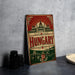 A vintage-style poster or sign displaying the word "HUNGARY" in large letters, with a depiction of the Hungarian capital city of Budapest in the background.