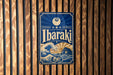 A vintage-style metal sign with the word "Ibaraki" displayed prominently in the center, featuring a wave and sun design.