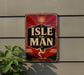 A vintage-style sign with the text "ISLE OF MAN" displayed prominently on a wall, with a sun and a figure of a man in the background.