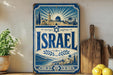 a vintage-style sign with the word "ISRAEL" prominently displayed, surrounded by a decorative border and a sunburst design. The sign is placed on a shelf next to a wooden cutting board and a potted plant, creating a homely and inviting atmosphere.