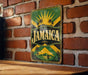A vintage Jamaica-themed metal sign is displayed on a brick wall, featuring a sun and palm tree design.