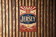 A vintage metal sign with the word "JERSEY" prominently displayed, featuring a red and white color scheme with a crown at the top.