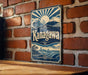 A vintage-style sign with the name "Kanagawa" displayed prominently, mounted on a brick wall.